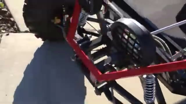 Red-painted go kart frame corner with engine and rear suspension