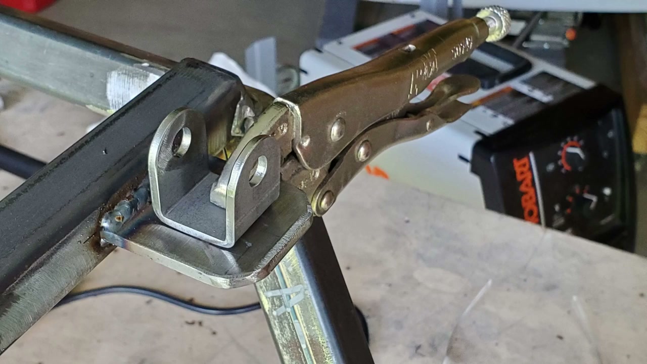 Welded suspension pivot bracket held with locking pliers on the go kart frame