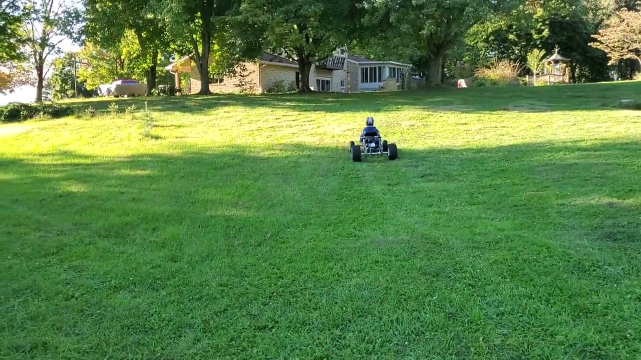 The finished Tarantula go kart being driven across a large grass field