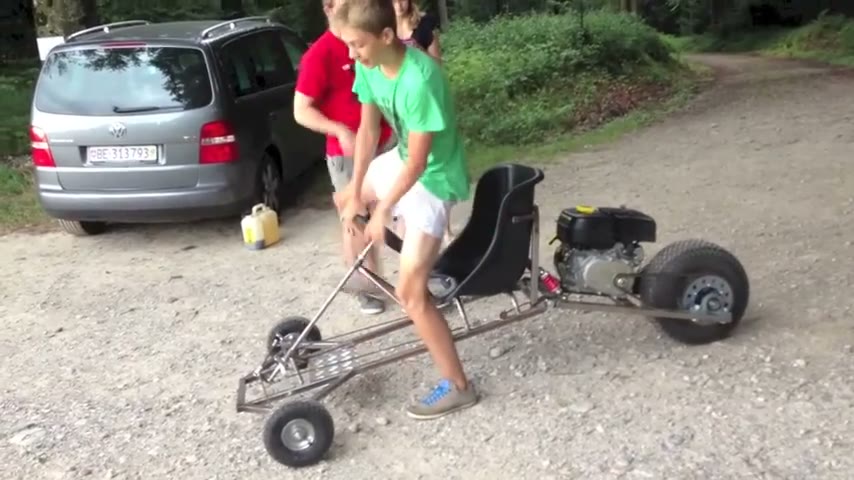 Young driver pull-starting the SpiderCart on a gravel road