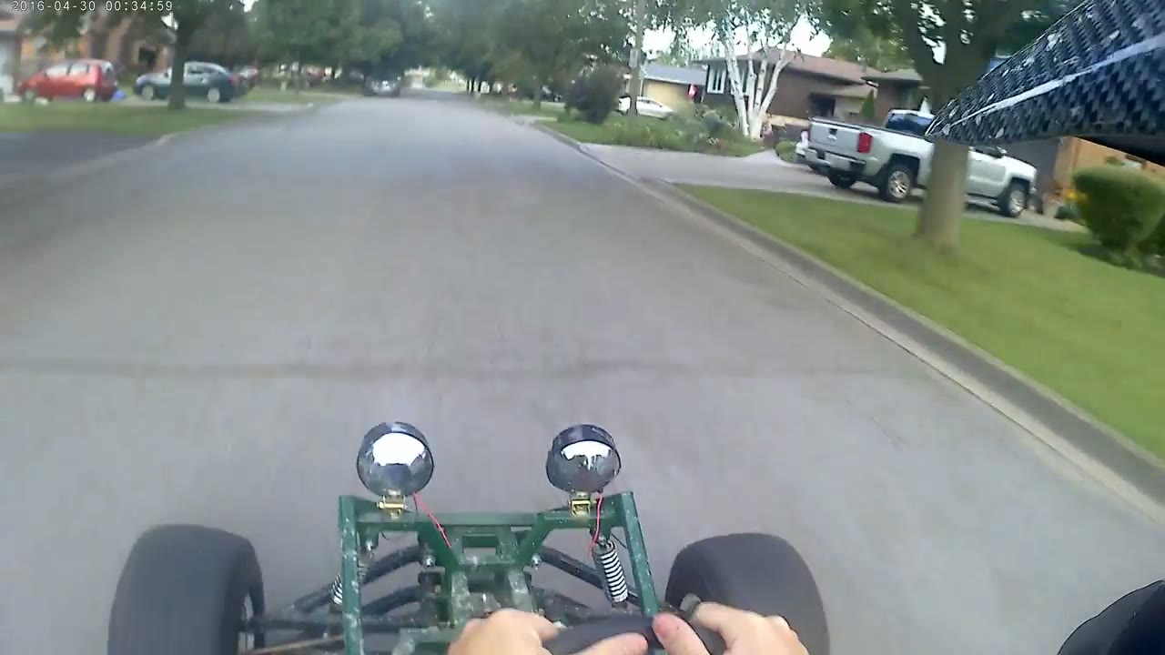 Helmet-cam view over the front of a green Arachnid on a street