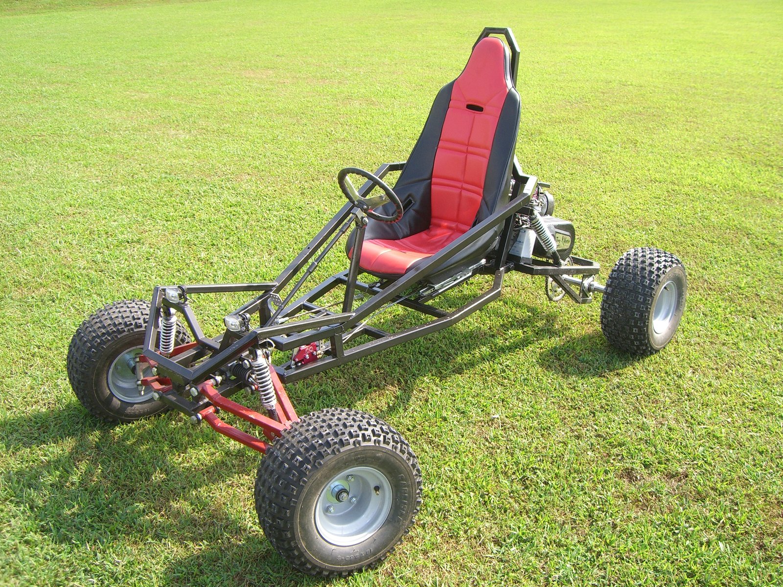 Finished Arachnid single-seat kart with a red seat, on grass